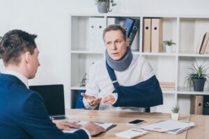 A man with a neck brace and his arm in a sling discussing the details of his case with a Valley Grande premises liability lawyer.