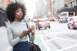 A woman is waiting for her Lyft with her phone in her hand. Call a Greensboro Lyft accident lawyer now.