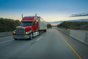A red semi truck drives on the highway in Greensboro. Call a Greensboro truck accident attorney now.