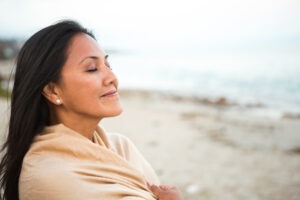 Woman feeling hopeful on beach smiling.