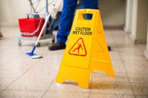 Someone mopping by a wet floor sign. Find out how to file a legal claim for damages with an Atlanta slip-and-fall lawyer.